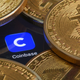 Coinbase logo on a computer screen surrounded by gold Bitcoin coins